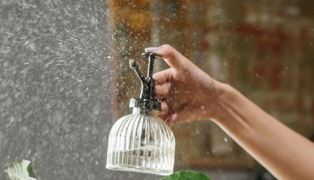 woman´s hand holding a glass container spraying water in the air